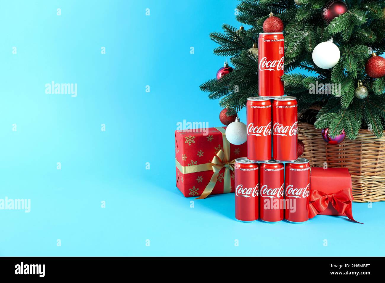 Odesses, Ukraine - 20 octobre 2021 : Composition arbre de Noël faite de canettes Coca-Cola et de boîtes-cadeaux, sur fond bleu Banque D'Images