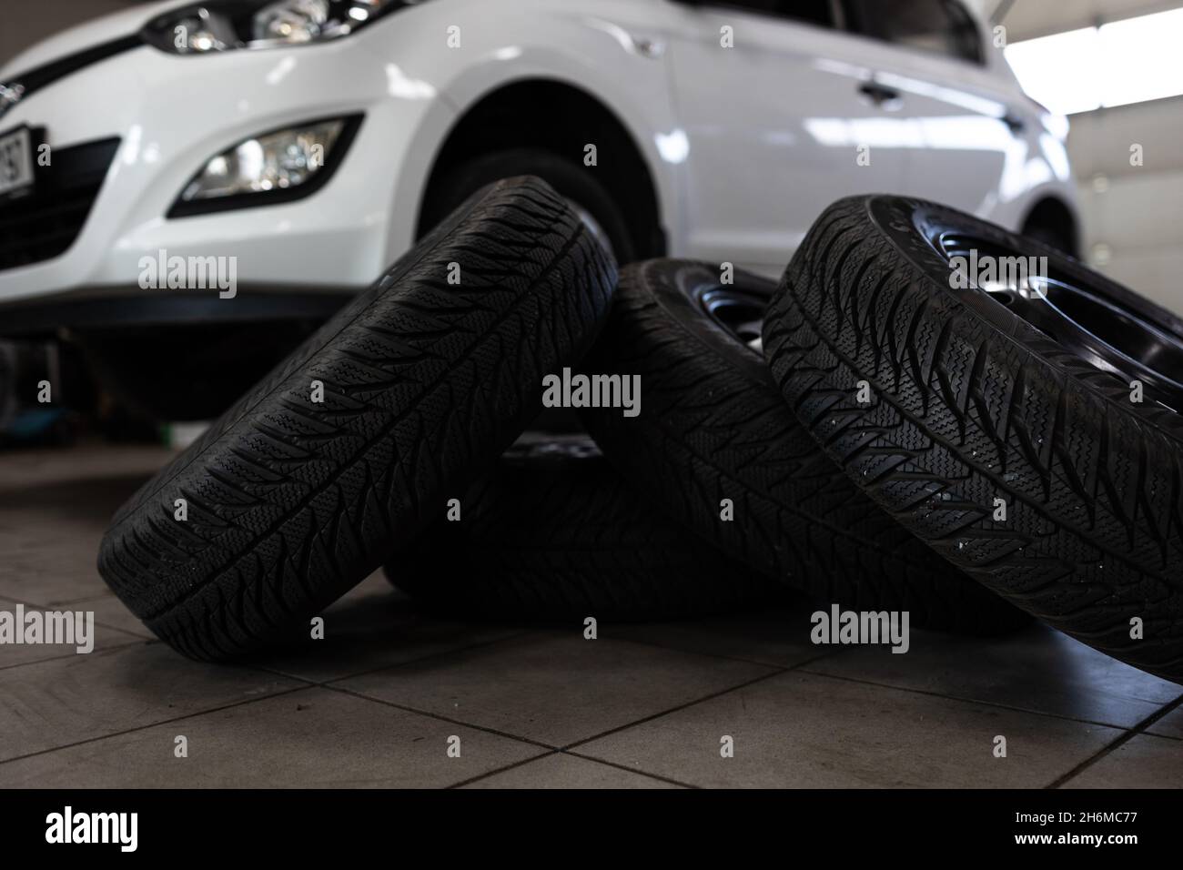 Voiture dans un garage pour l'entretien, l'huile, le changement de pneu (DOF peu profond; image colorée) Banque D'Images