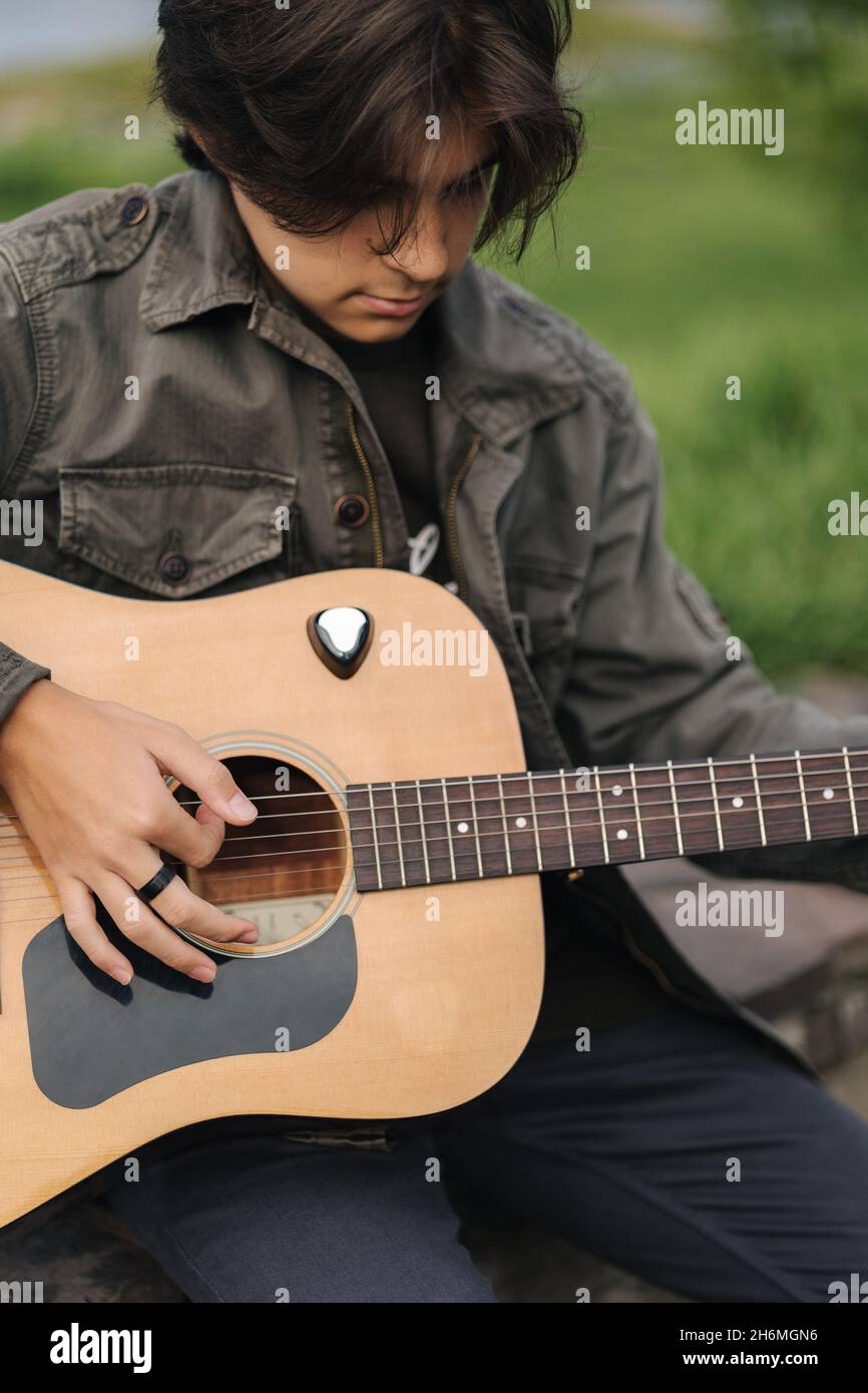 Portrait d'un jeune garçon de belle adolescence jouant de la guitare à l'extérieur.Garçon utilisant la guitare classique.Homme seul faisant de la musique Banque D'Images