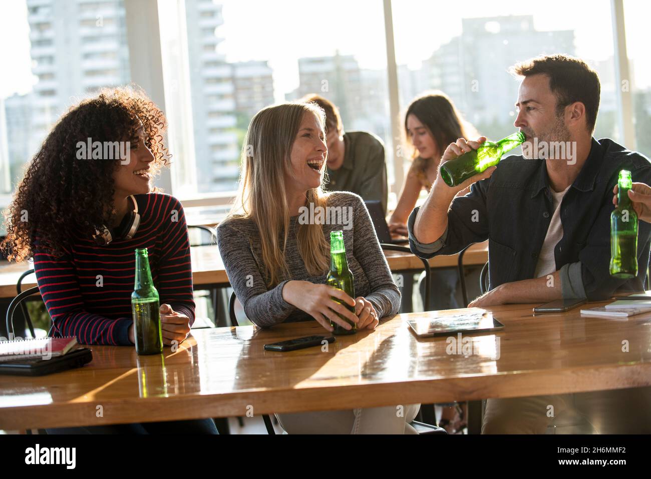 Des gens d'affaires souriants qui ont une bière au bureau Banque D'Images