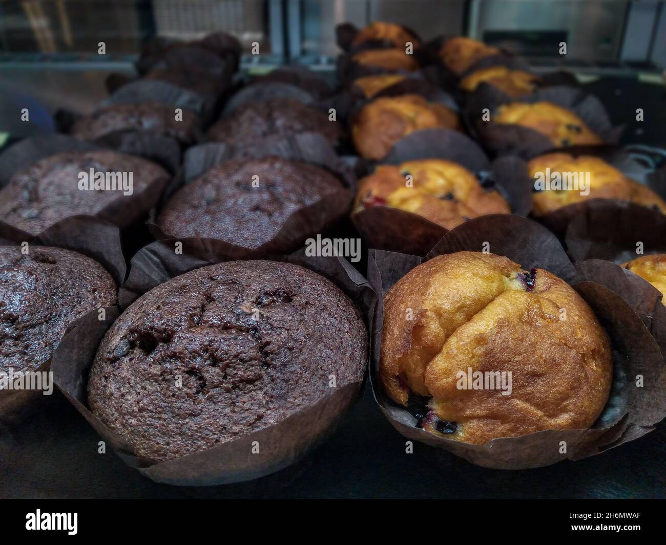 Muffins à la vanille et au chocolat en papier brun sur une vitrine de café-boutique, concept Banque D'Images