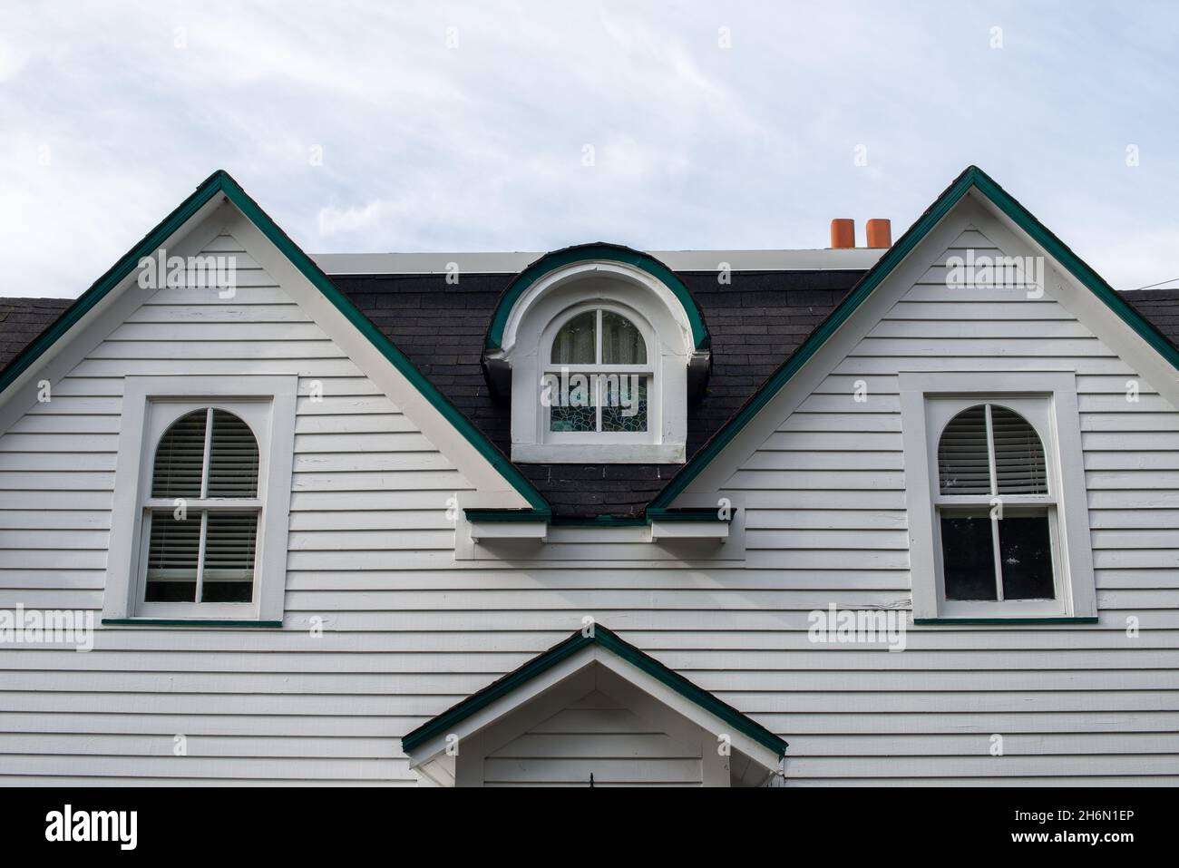 Un panneau en bois blanc parement maison ancienne avec plusieurs fenêtres.La fenêtre centrale est dotée d'un dormeur courbé sur la vitre en verre fermée dans le noir Banque D'Images