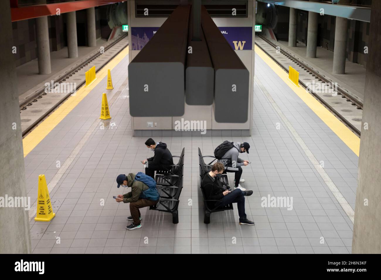 Les passagers utilisent leur téléphone cellulaire en attendant le prochain train à la nouvelle gare Link Light Rail U District Station de Seattle le mardi 16 novembre 202 Banque D'Images