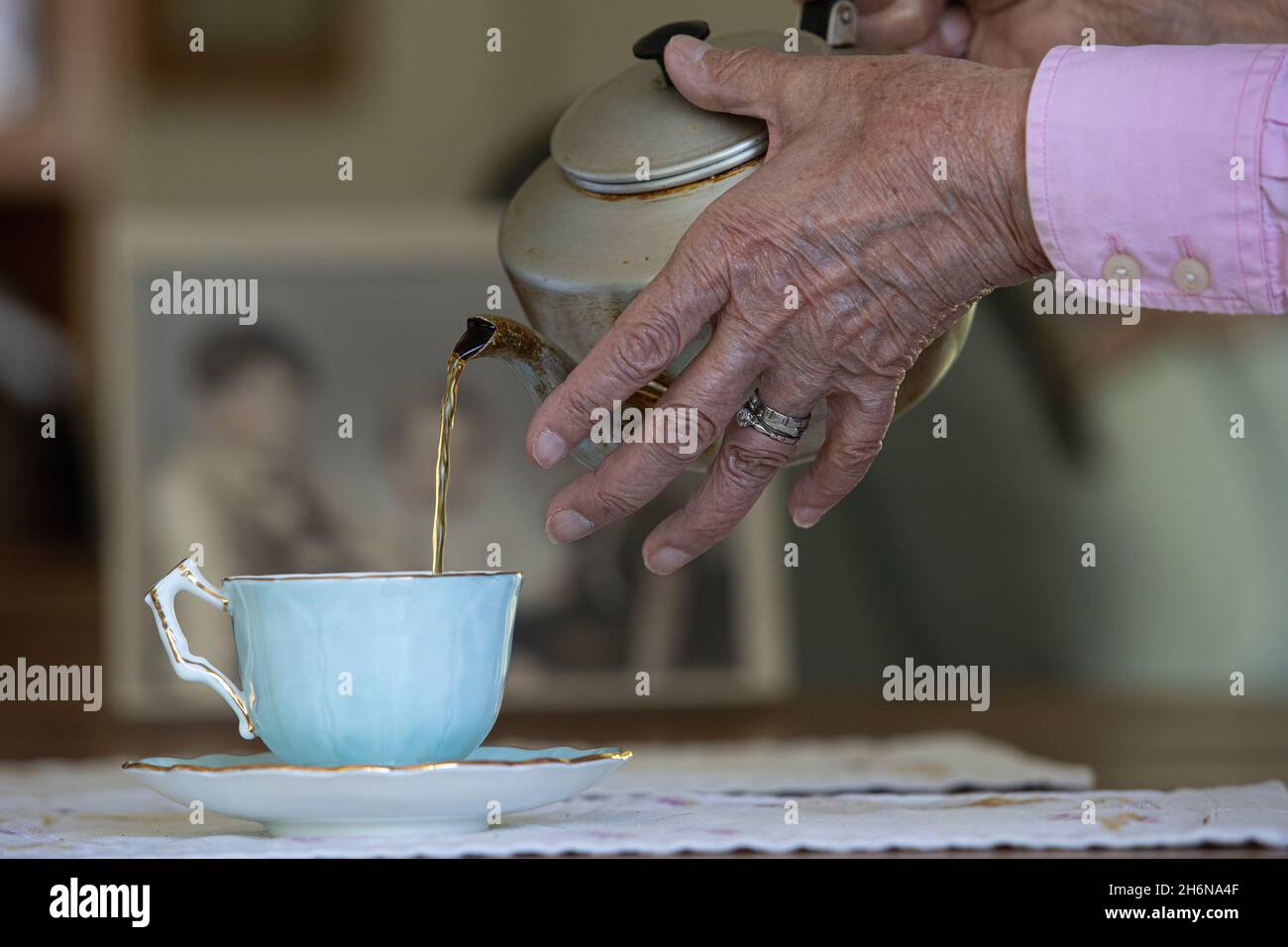 Photo générique d'une vieille main femelle versant une tasse de thé d'un pot dans une tasse de porcelaine. Banque D'Images