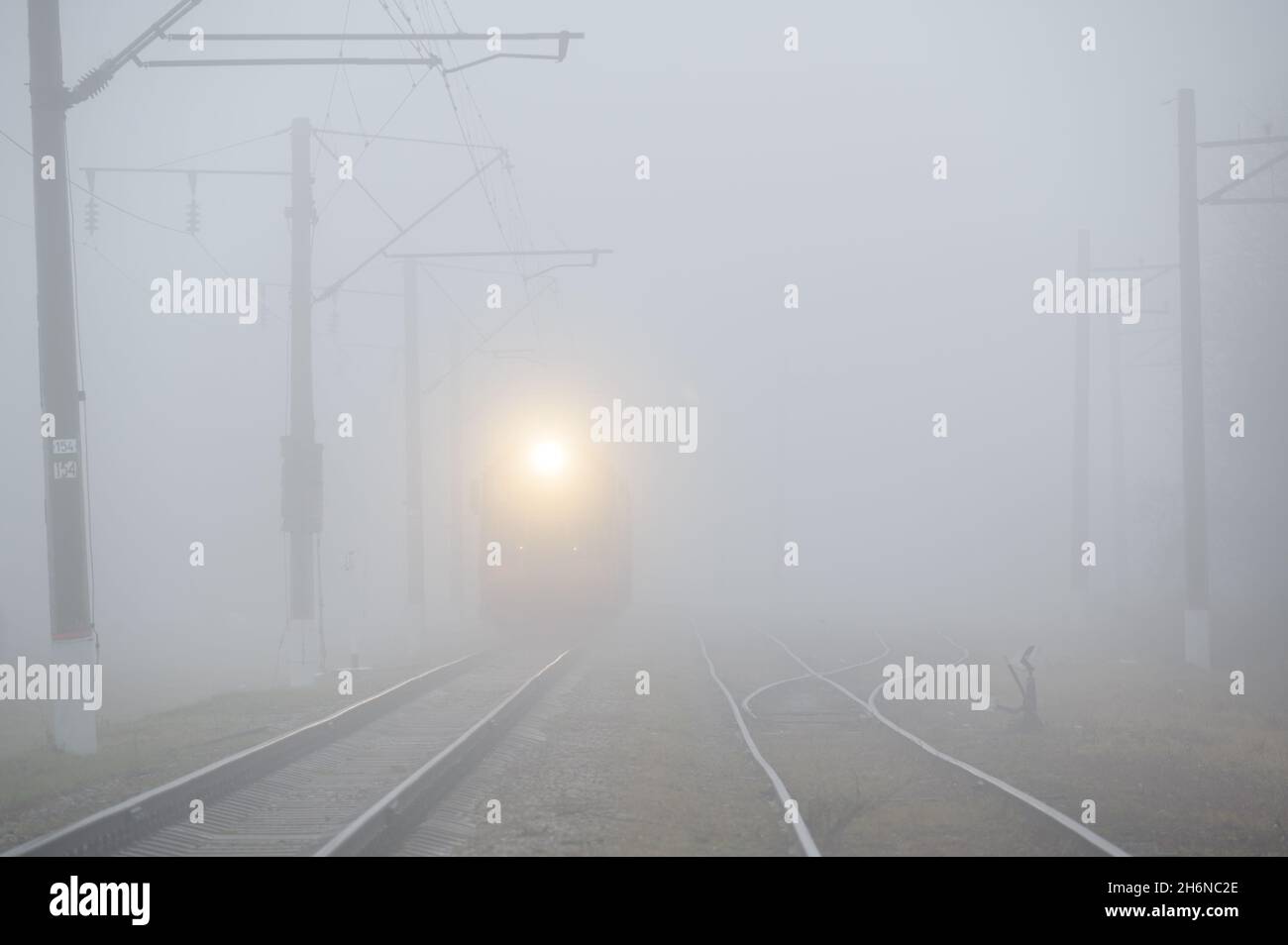 train de nuit avec lumière chaude jaune sur le chemin de fer dans un brouillard sombre Banque D'Images