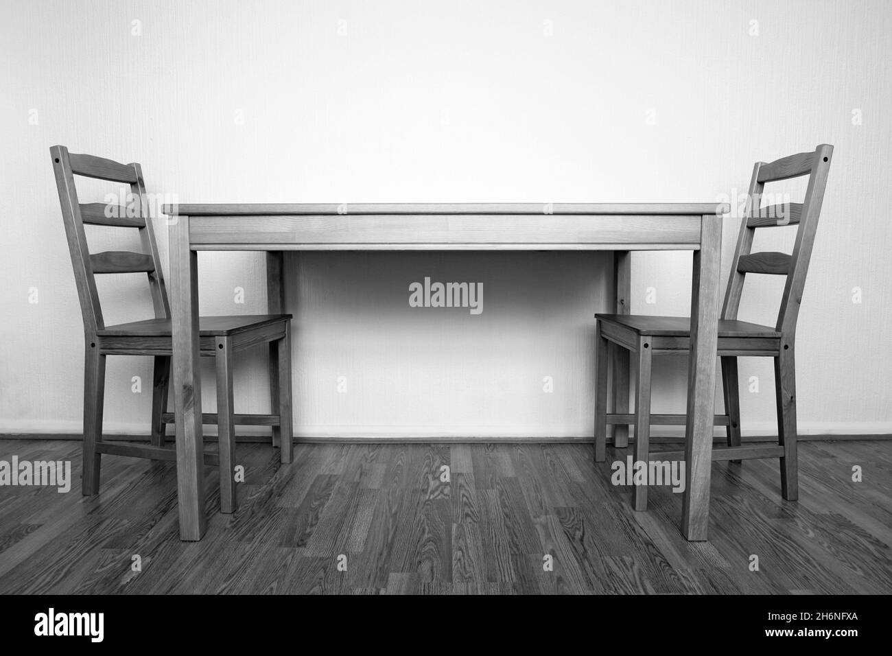 Photographie en noir et blanc d'un intérieur simple avec deux chaises en bois et une table sur un plancher en bois Banque D'Images