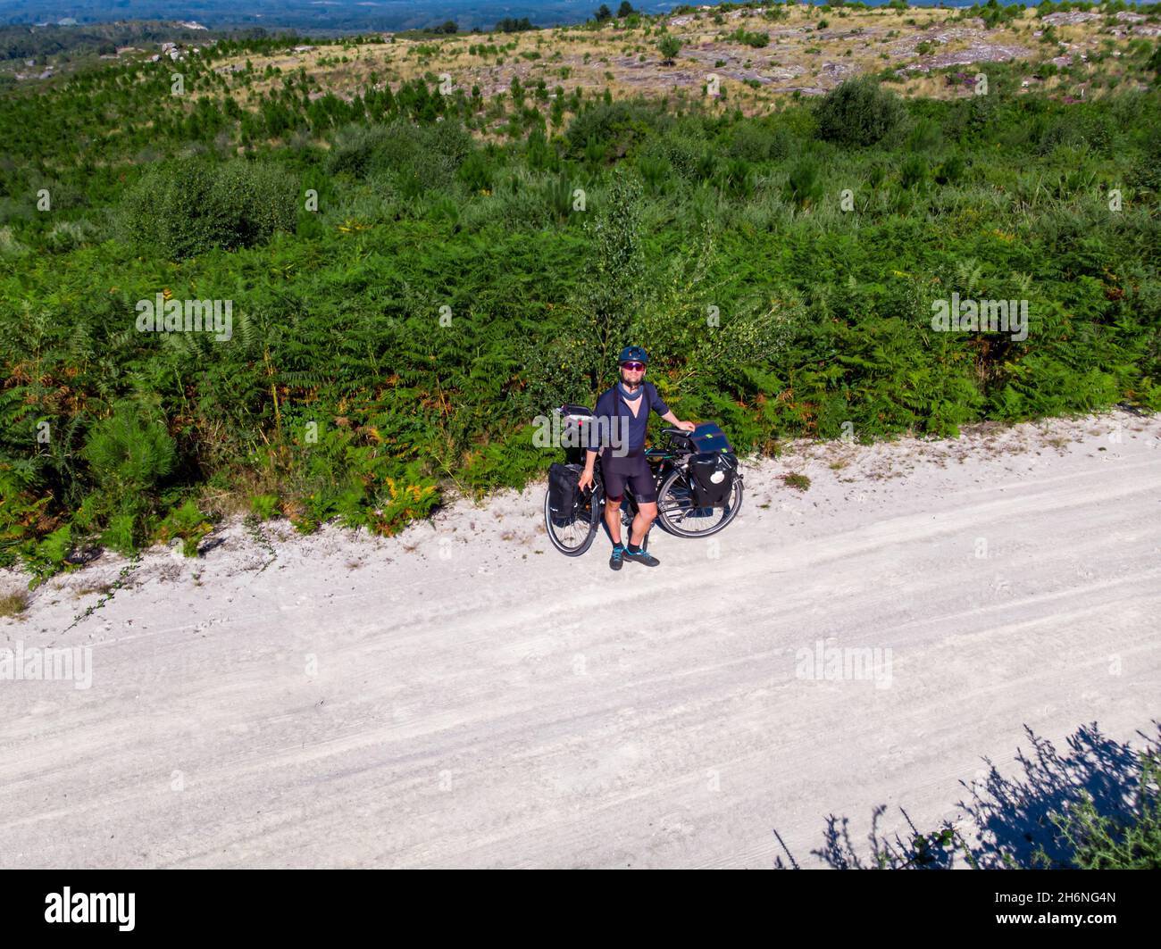 Cycliste aventureux caucasien posant sur la route avec son vélo Banque D'Images