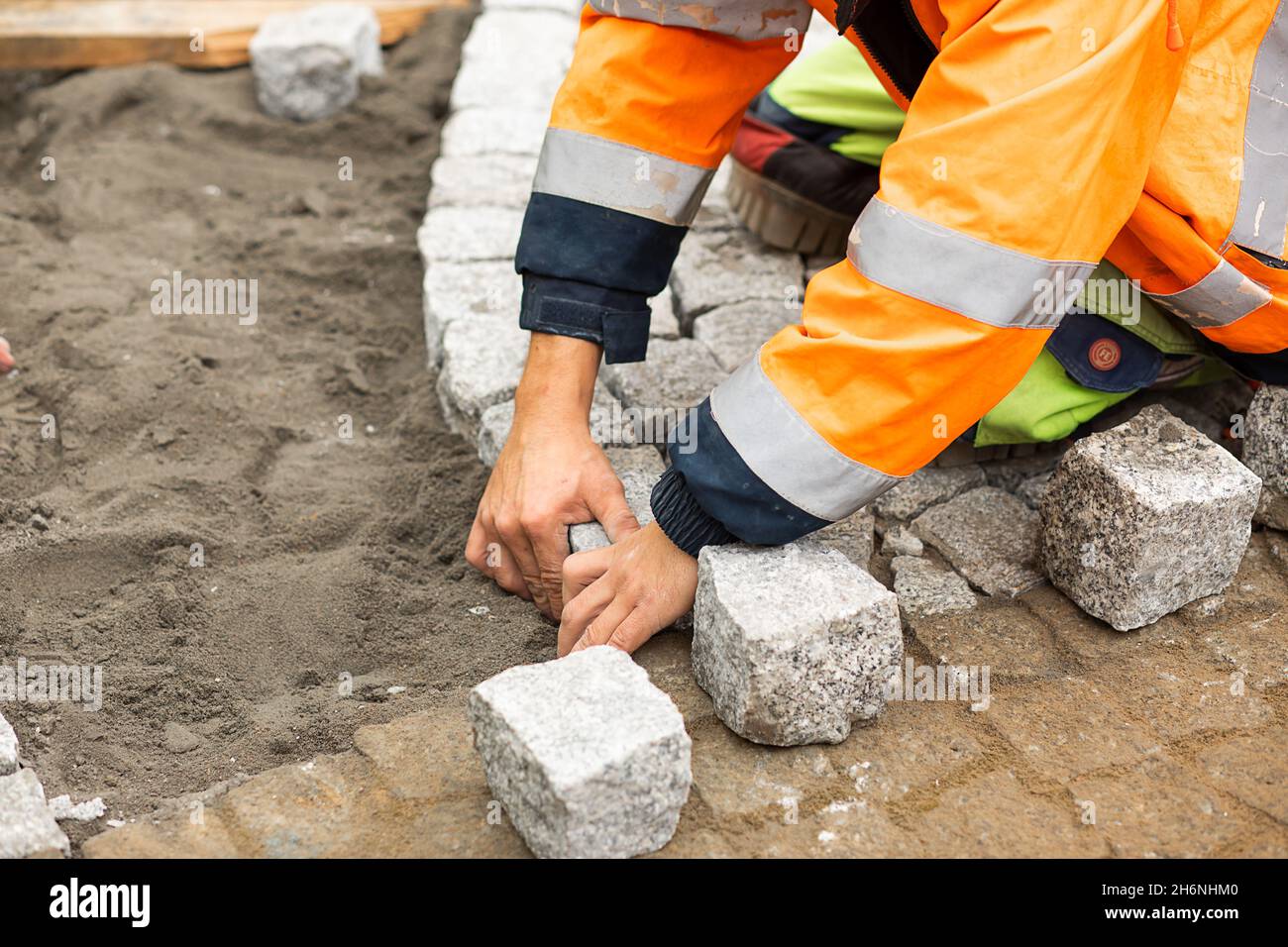 Travaux d'entretien sur le pavage avec pavés emboîtés.Personne méconnaissable avec des matériaux de construction en main, des produits en béton, l'industrie du bâtiment Banque D'Images