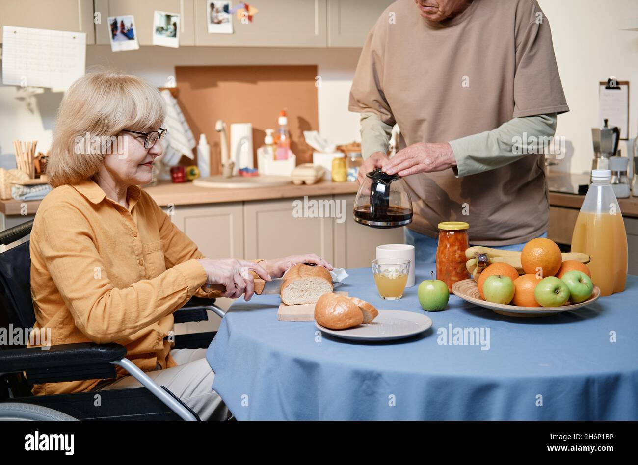 Un couple senior prépare le petit déjeuner à la table dans la cuisine Banque D'Images