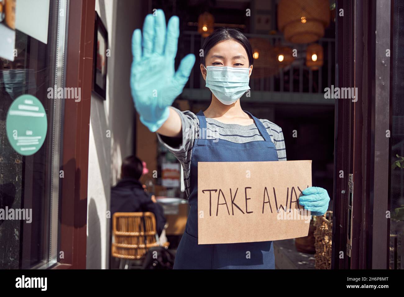 Femme asiatique tenant un panneau à emporter devant la porte du café Banque D'Images