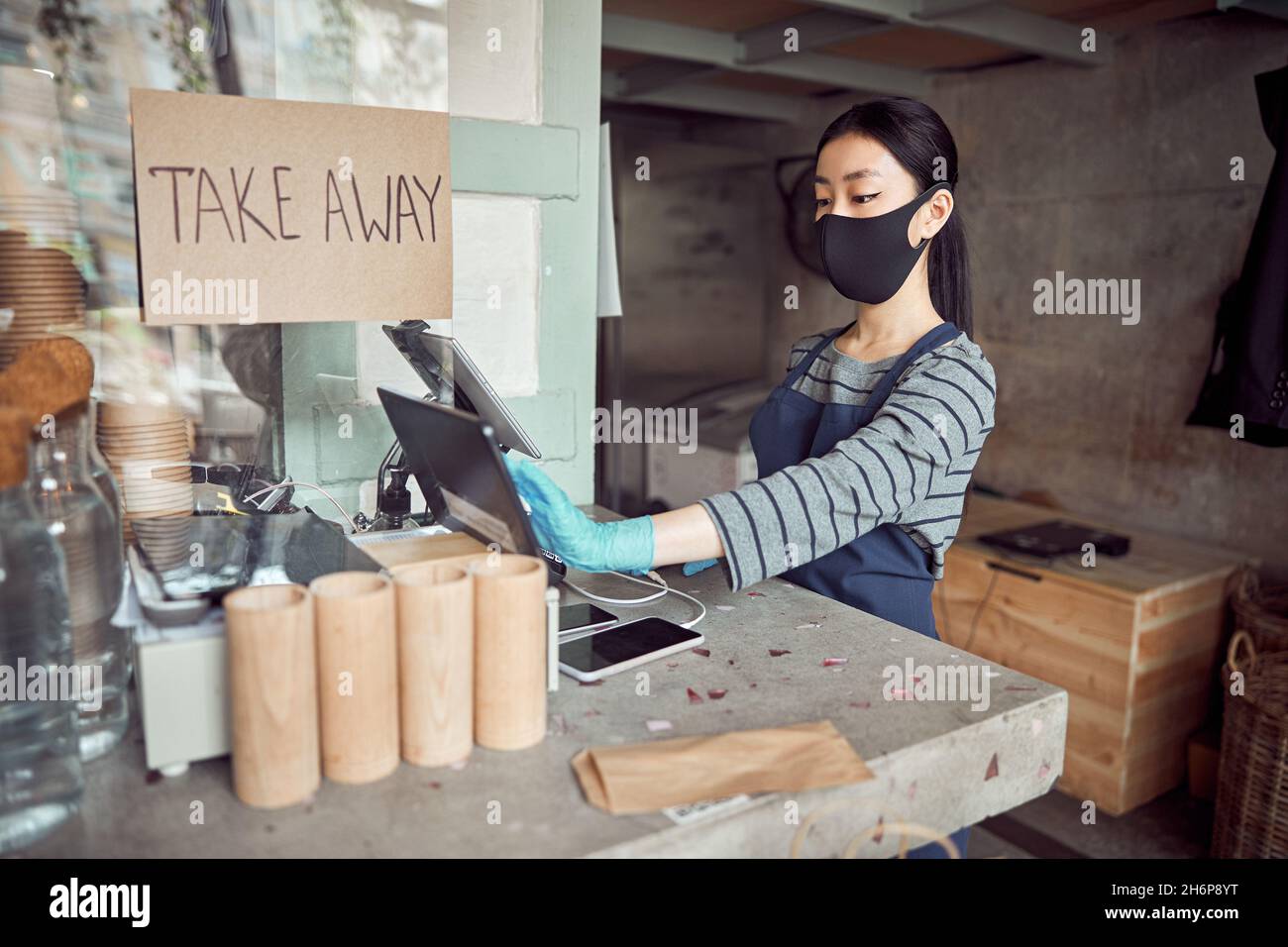Barista dans un masque de protection travaillant dans un café Banque D'Images