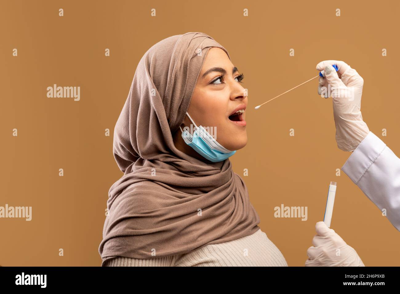 Une femme musulmane obtient un test d'écouvillonnage PCR oral du coronavirus, une femme médecin effectuant un test d'écouvillonnage Covid-19 depuis la gorge pour le patient Banque D'Images
