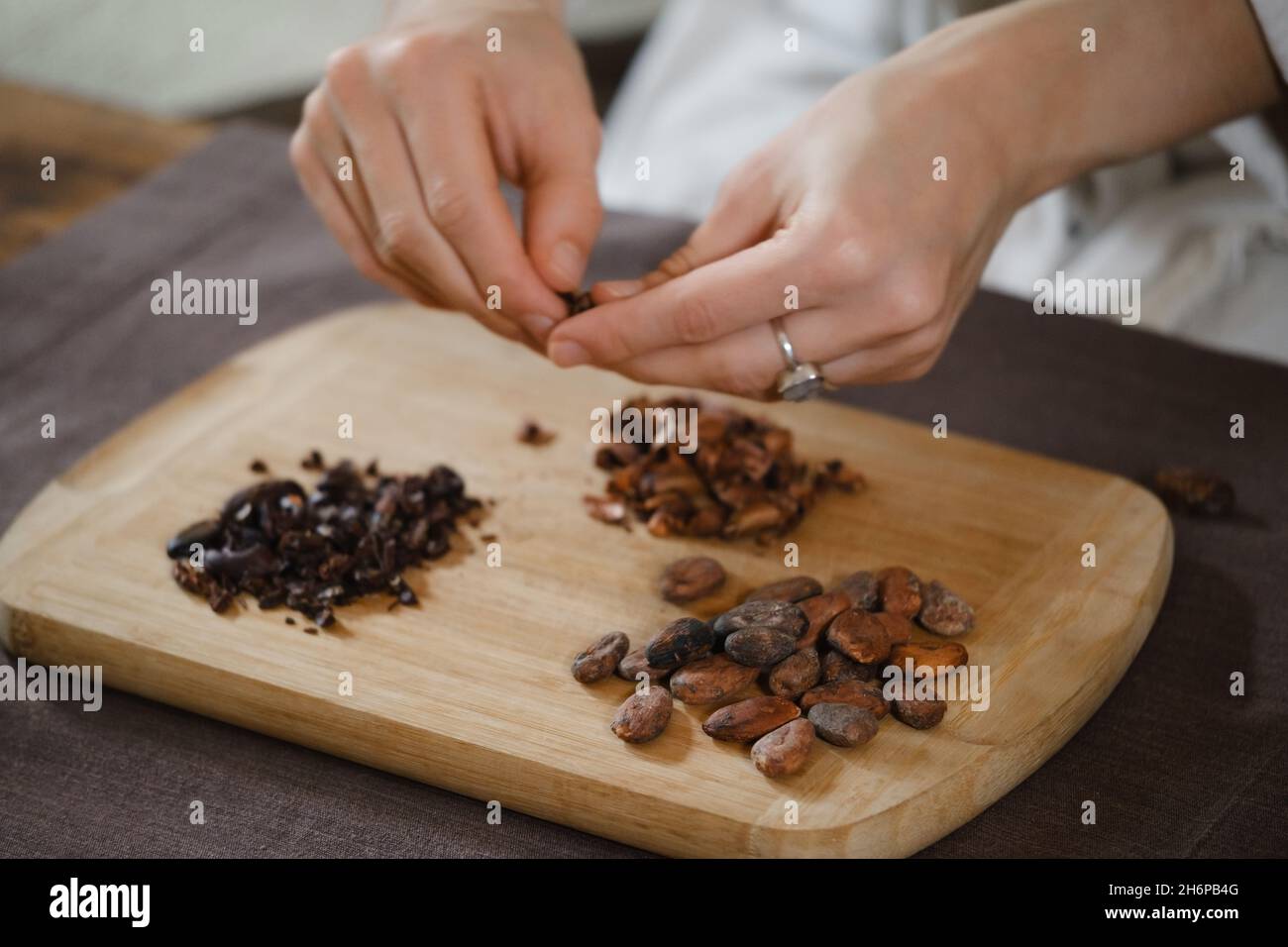 Les mains épluchant des haricots cacao bio sur une table en bois, des pointes de cacao, la fabrication artisanale de chocolat dans un style rustique pour la cérémonie sur la table.Dégustation Banque D'Images