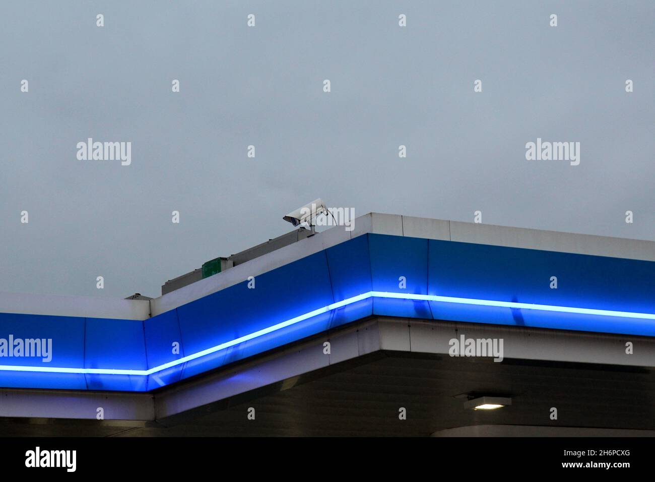 Blau beleuchtetes Dach mit einer Überwachungskamera einer ARAL Tankstelle BEI Nacht. Banque D'Images
