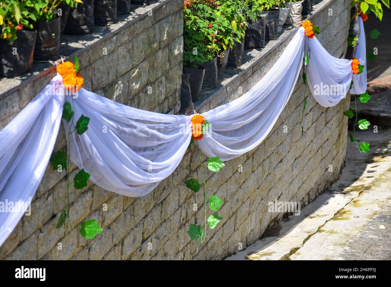 Mur en pierre décoré avec une fleur de marigold, une fleur en pot et un tissu blanc. Banque D'Images