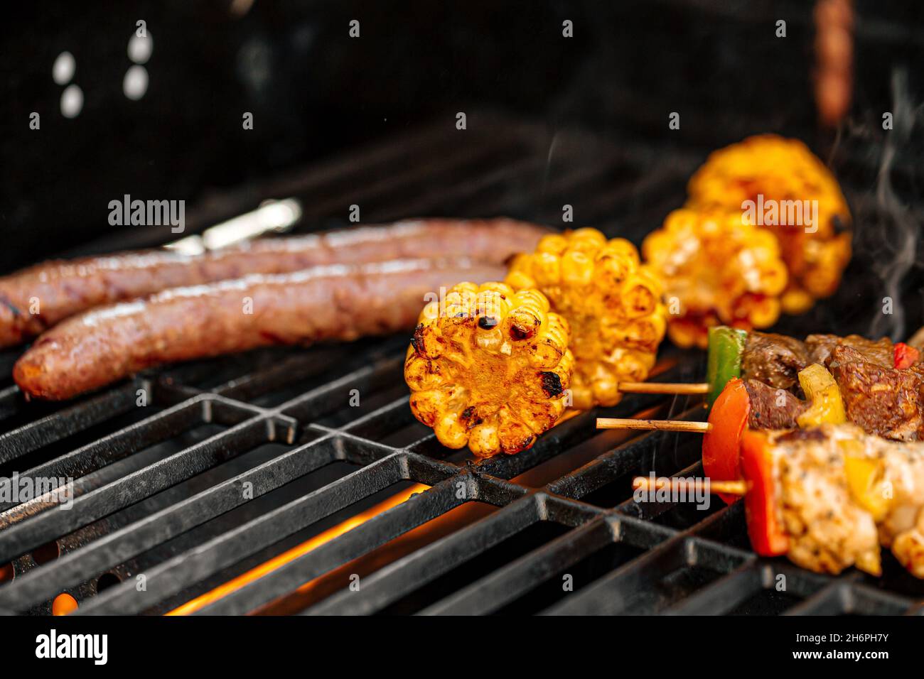 Griller des brochettes de poulet et du maïs sur un barbecue Banque D'Images
