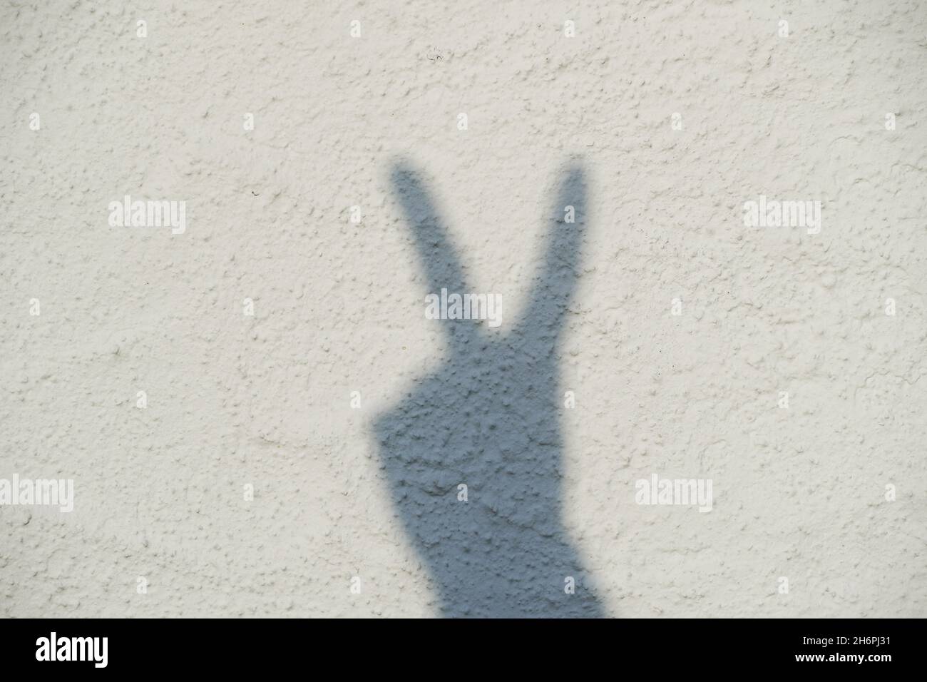 Ombre d'une main sur un mur blanc.Signe de paix.Panneau Victorry. Banque D'Images