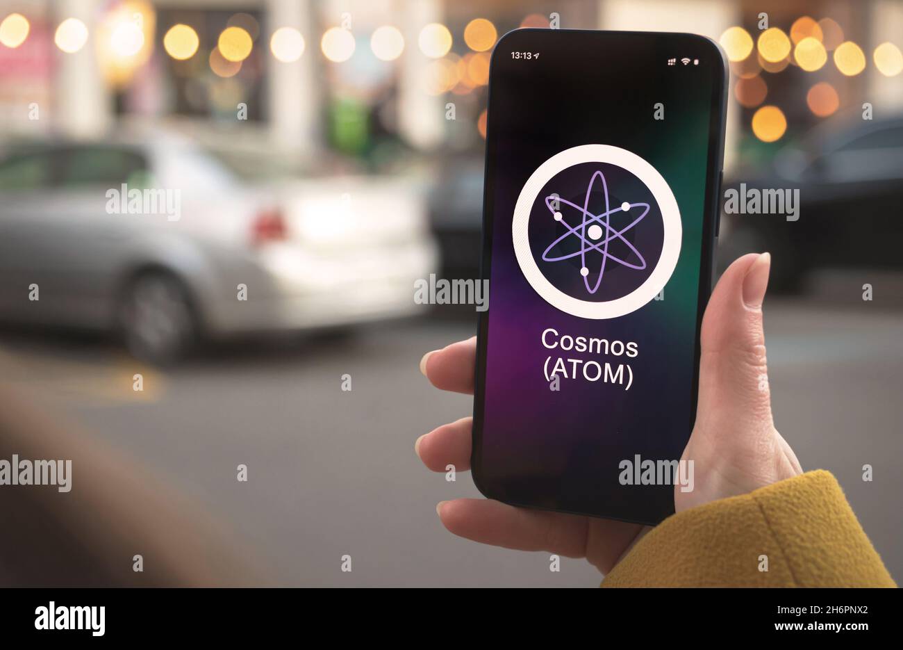 Symbole de crypto-monnaie ATOM COSMOS, logo.Concept commercial et financier.Main avec smartphone, écran avec icône de chiffrement en gros plan Banque D'Images