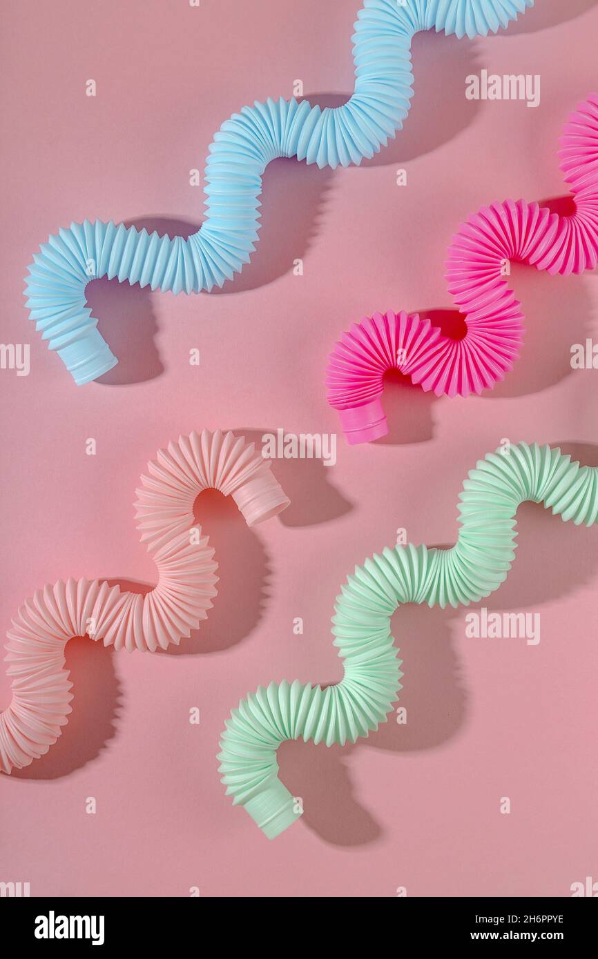 Tube pop courbé rose bleu menthe antistress jouet avec ombre sur fond rose.Jouet brillant pour enfants Banque D'Images