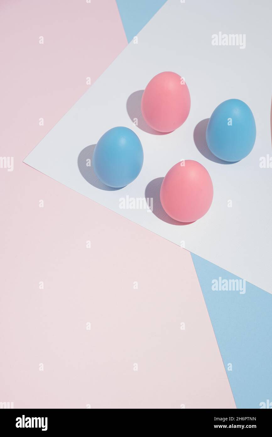 Composition moderne minimaliste Pâques avec quatre œufs roses et bleus sur fond pastel, avec espace copie.Format vertical. Banque D'Images