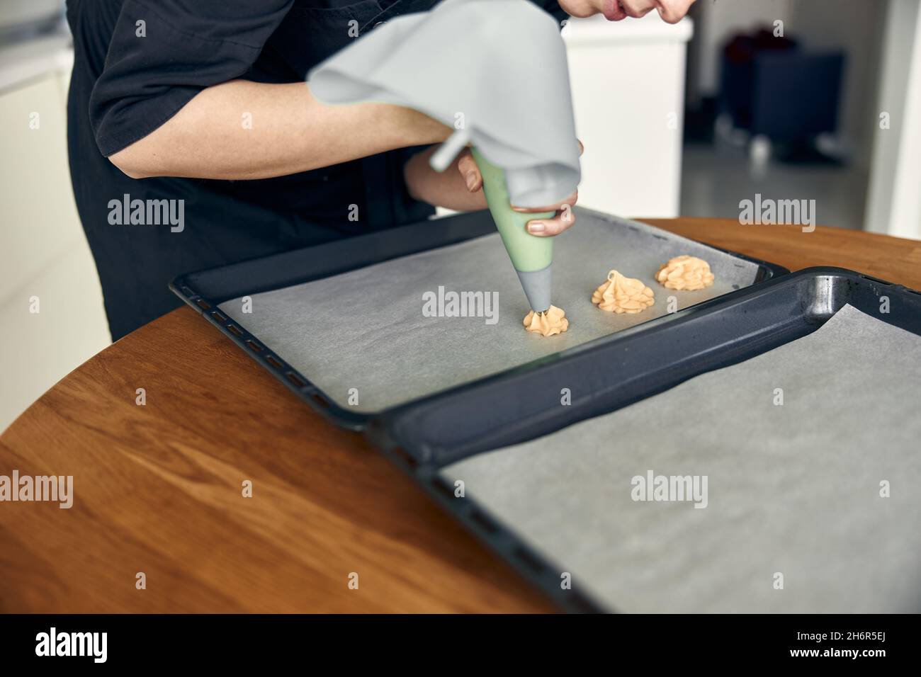 belle femme de cuisine caucasienne fait des eclairs avec l'aide de pâtisserie tubage à la maison Banque D'Images