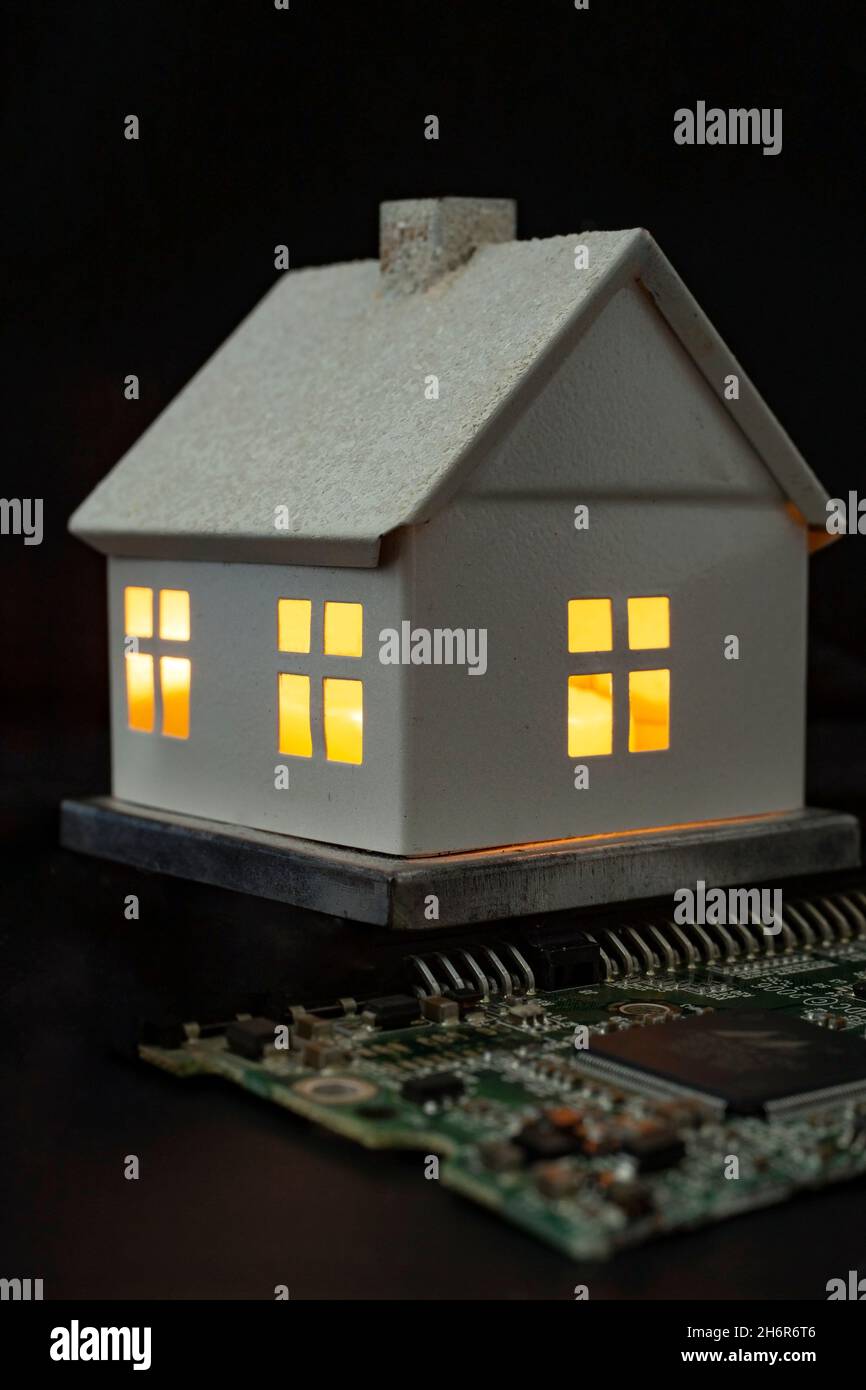 concept de maison intelligente, maison miniature connectée à une carte mère, isolée sur noir Banque D'Images