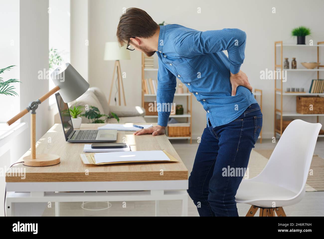 L'homme qui travaille assis devant son ordinateur tout le temps souffre de douleurs dorsales Banque D'Images