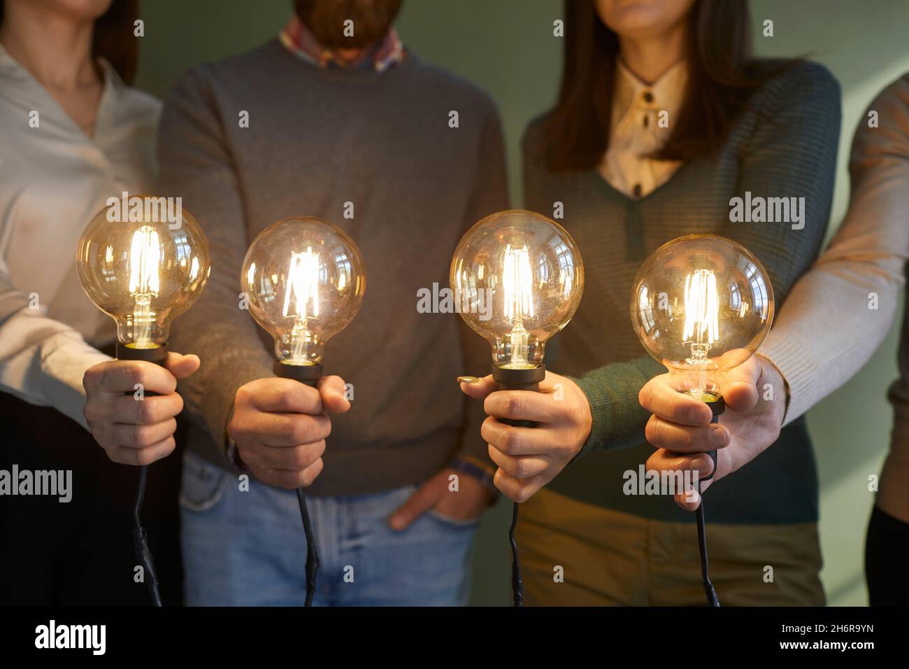 Équipe de personnes tenant des ampoules pour montrer le concept des idées créatives et des innovations Banque D'Images
