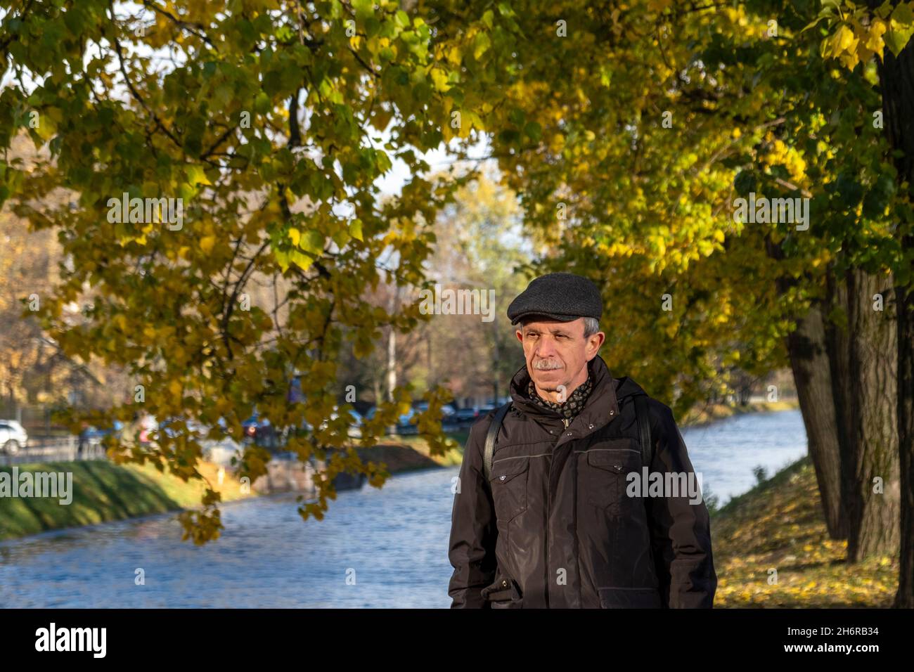 Le retraité âgé se tient en belle journée d'automne dans le parc de la ville Banque D'Images
