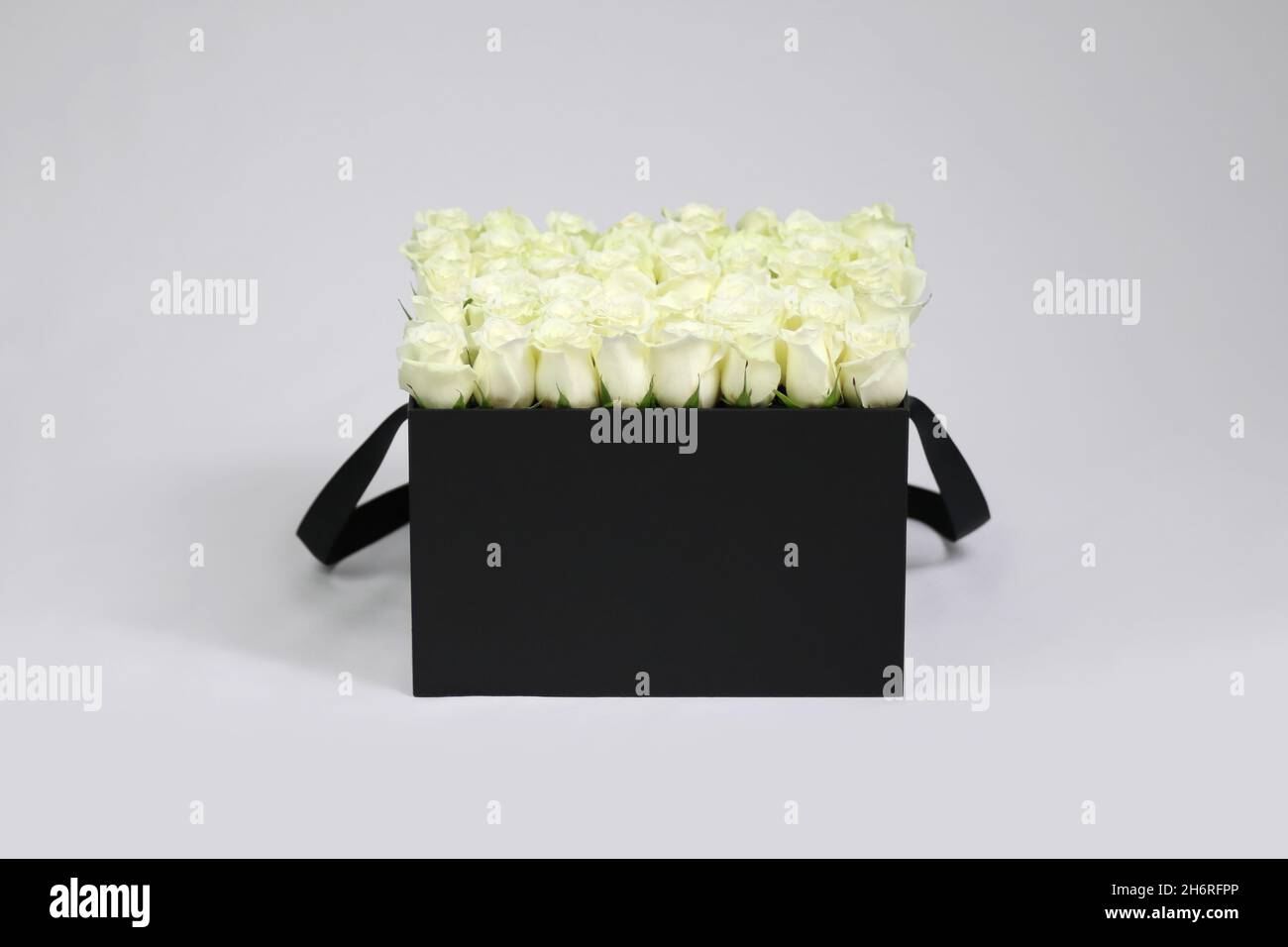 Boîte cadeau à fleurs carrée noire avec roses blanches à l'intérieur Banque D'Images