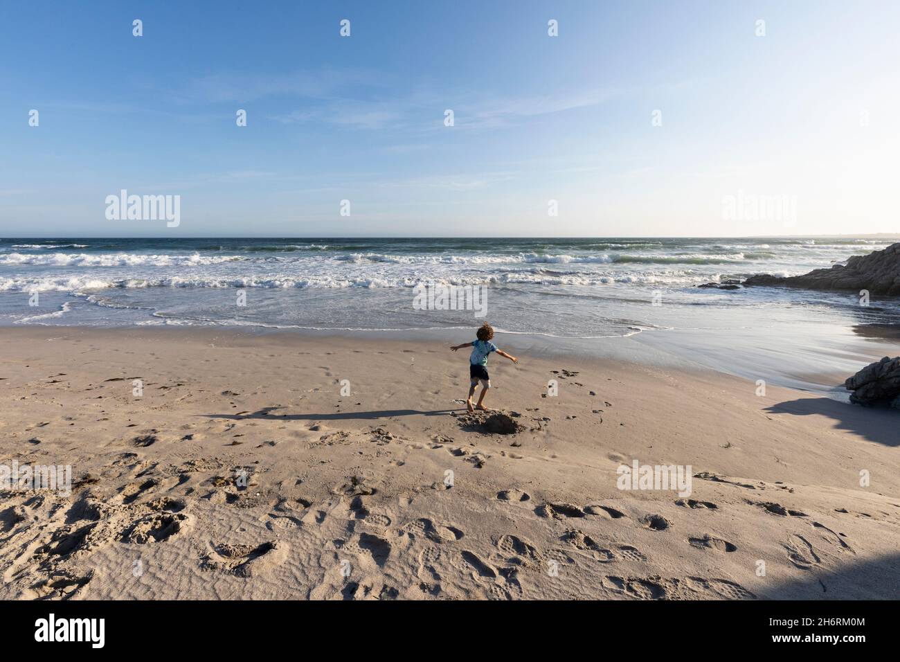 Jeune garçon qui court dans un espace ouvert sur une plage de la côte atlantique. Banque D'Images