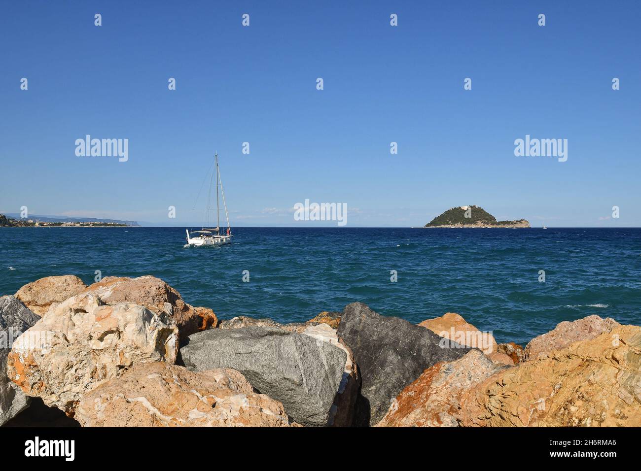 Paysage marin d'une falaise rocheuse avec un voilier en navigation vers l'île de Gallinara en été, Alassio, Savona, Ligurie, Italie Banque D'Images