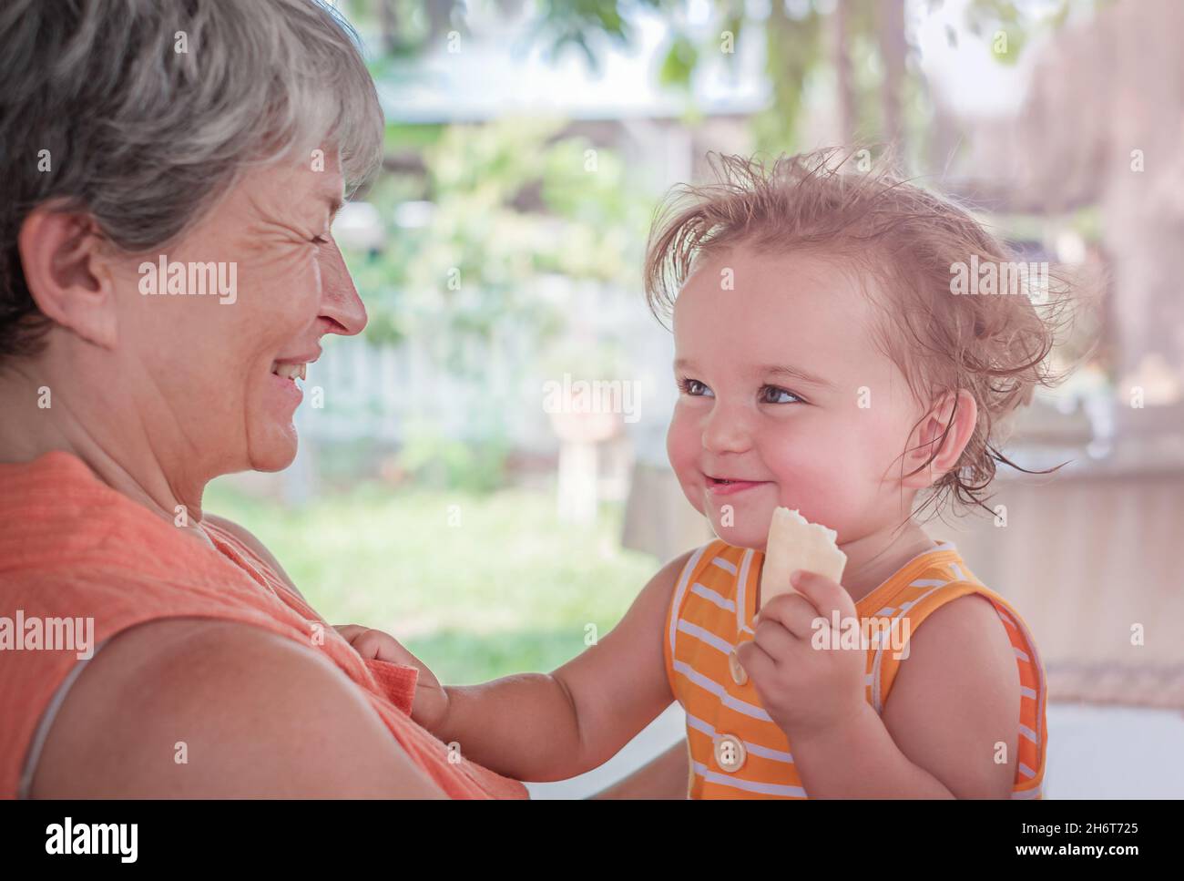 L'enfant dans les bras de la grand-mère tient un cookie dans ses mains Banque D'Images