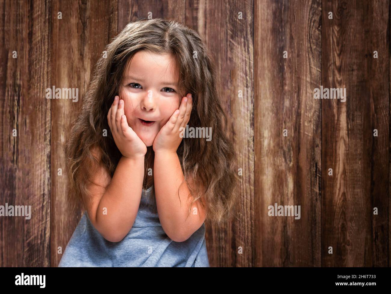 Portrait de l'enfant heureux surpris fille sur fond de bois Banque D'Images