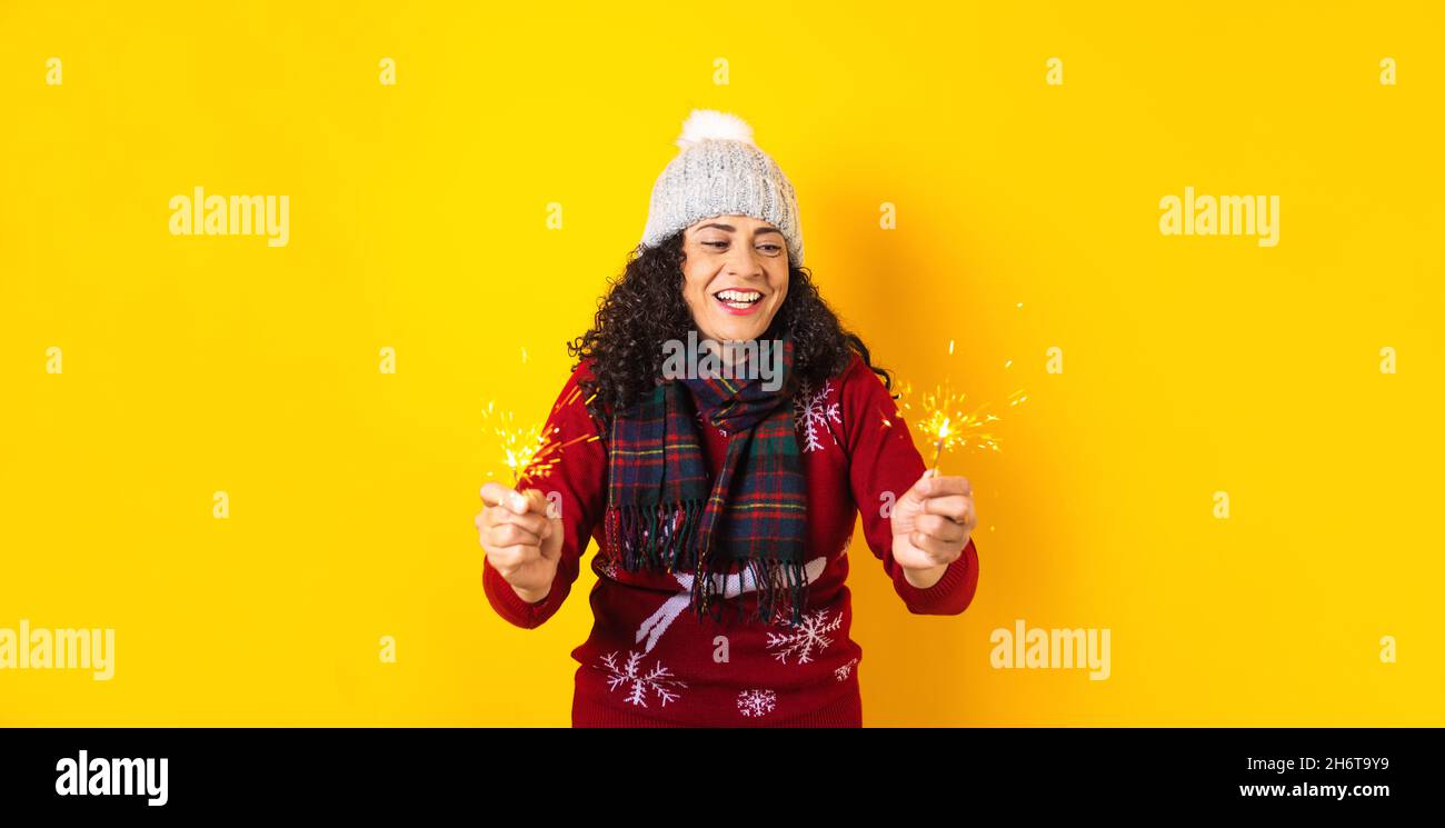 Femme hispanique adulte tenant des lumières pétillantes de noël pour la posada mexicaine à noël sur fond jaune au Mexique Amérique latine Banque D'Images