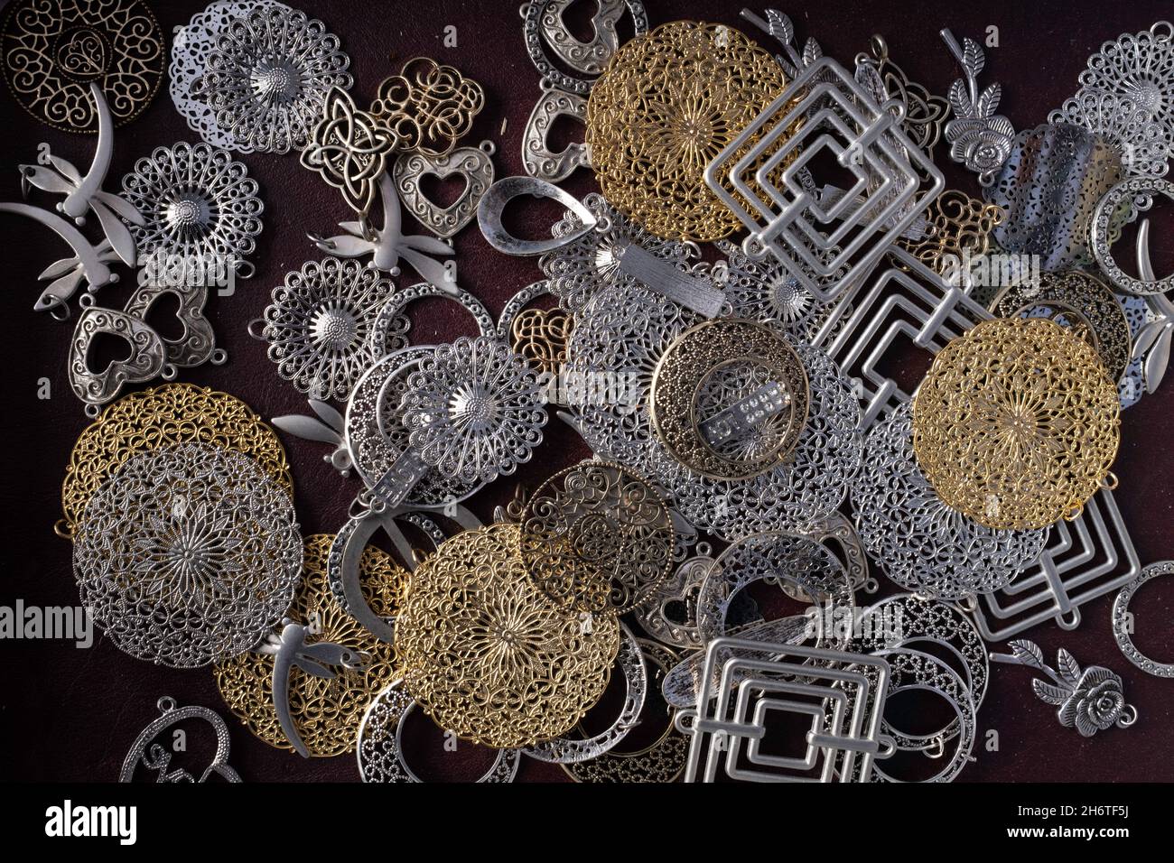 Beaux pendentifs ronds et ovales de couleur or et argent finement travaillés pour sur une chaîne, bijoux bon marché sur un marché avec fond noir Banque D'Images