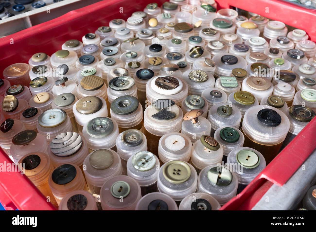 Boutons de toutes formes, matériaux, tailles et couleurs dans des tubes en plastique dans un stalle de marché.Concentrez-vous sur les boutons situés en bas, à l'avant de la boîte Banque D'Images
