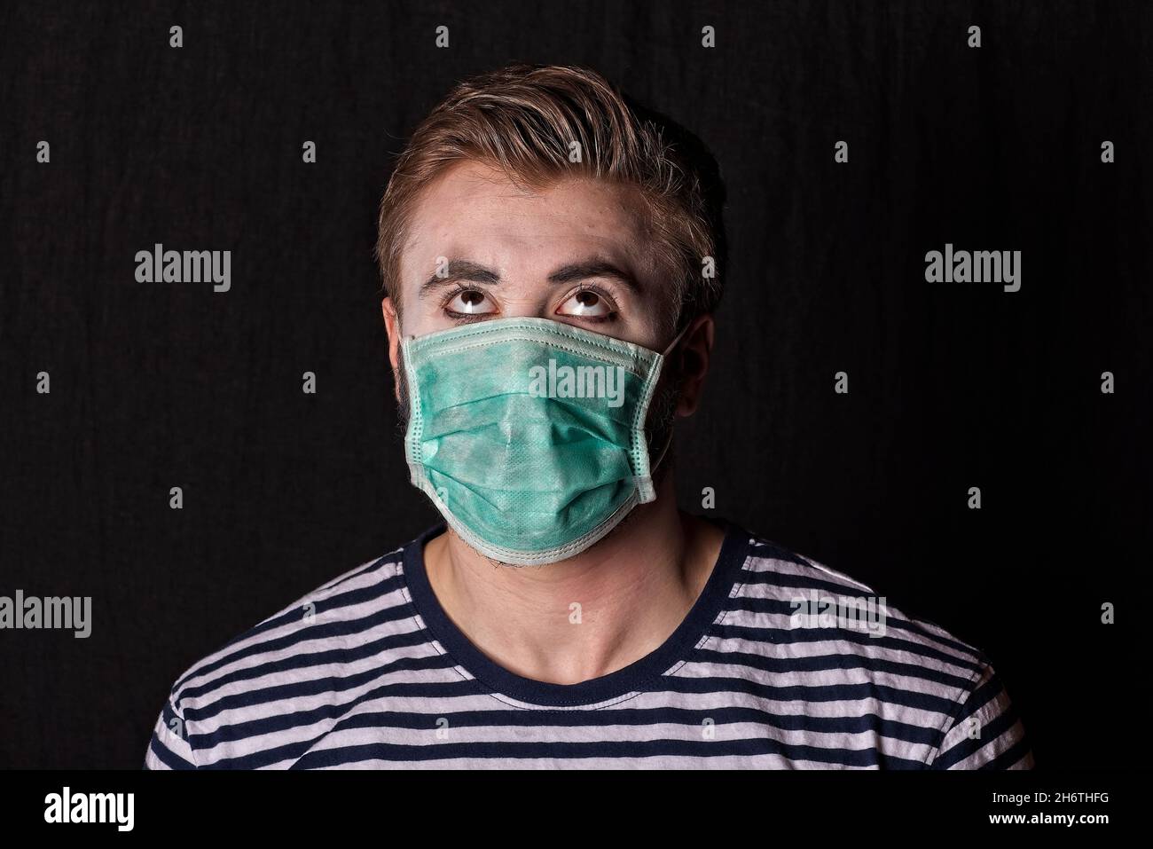 Jeune homme mime artiste haut du thorso et de la tête, en roulant les yeux vers le haut tout en portant un masque médical pendant le couronnement du coronavirus pandemy quand dans certains pays face à c Banque D'Images