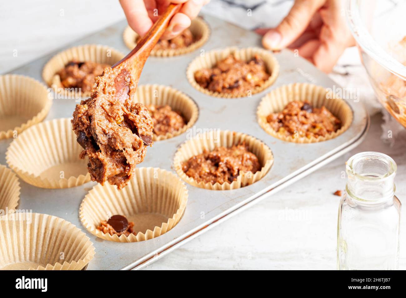 fabrication de délicieux fruits et cupcake aux noix sur fond de comptoir en marbre blanc.Moule à muffins avec doublure, ingrédients et ustensiles.Une femme est Banque D'Images
