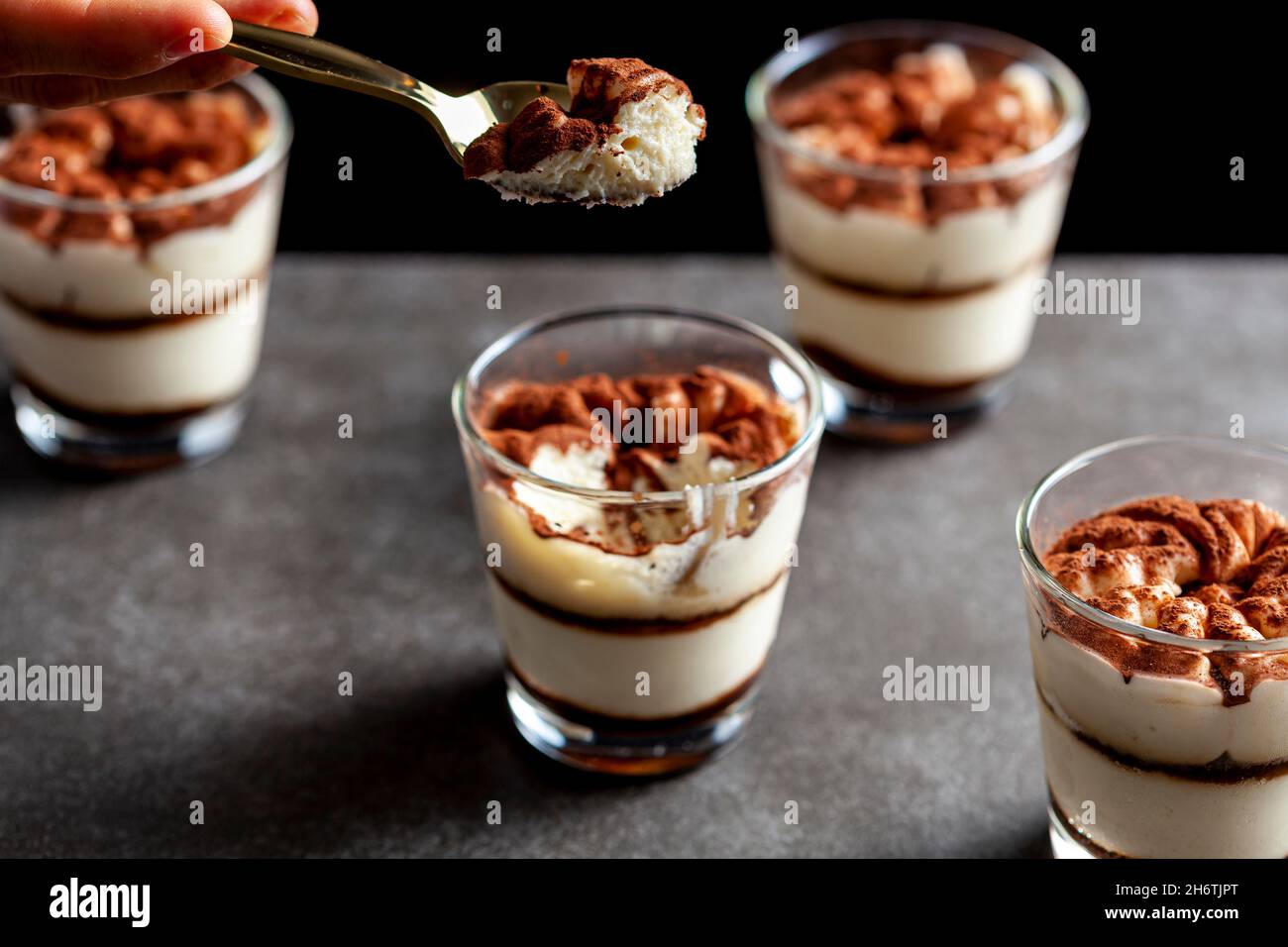 Délicieux dessert traditionnel tiramisu servi dans de petites tasses en verre sur un comptoir en pierre.L'image en basse lumière montre la texture et les couches sous l'angle du shallo Banque D'Images