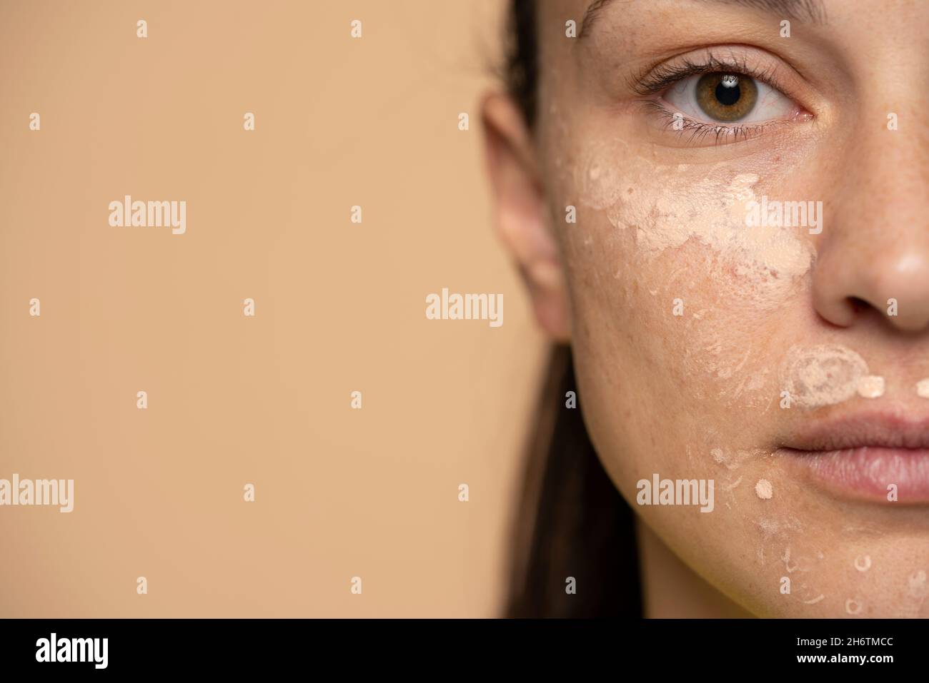 Gros plan de la jeune femme avec le correcteur sur son visage sur un fond beige Banque D'Images
