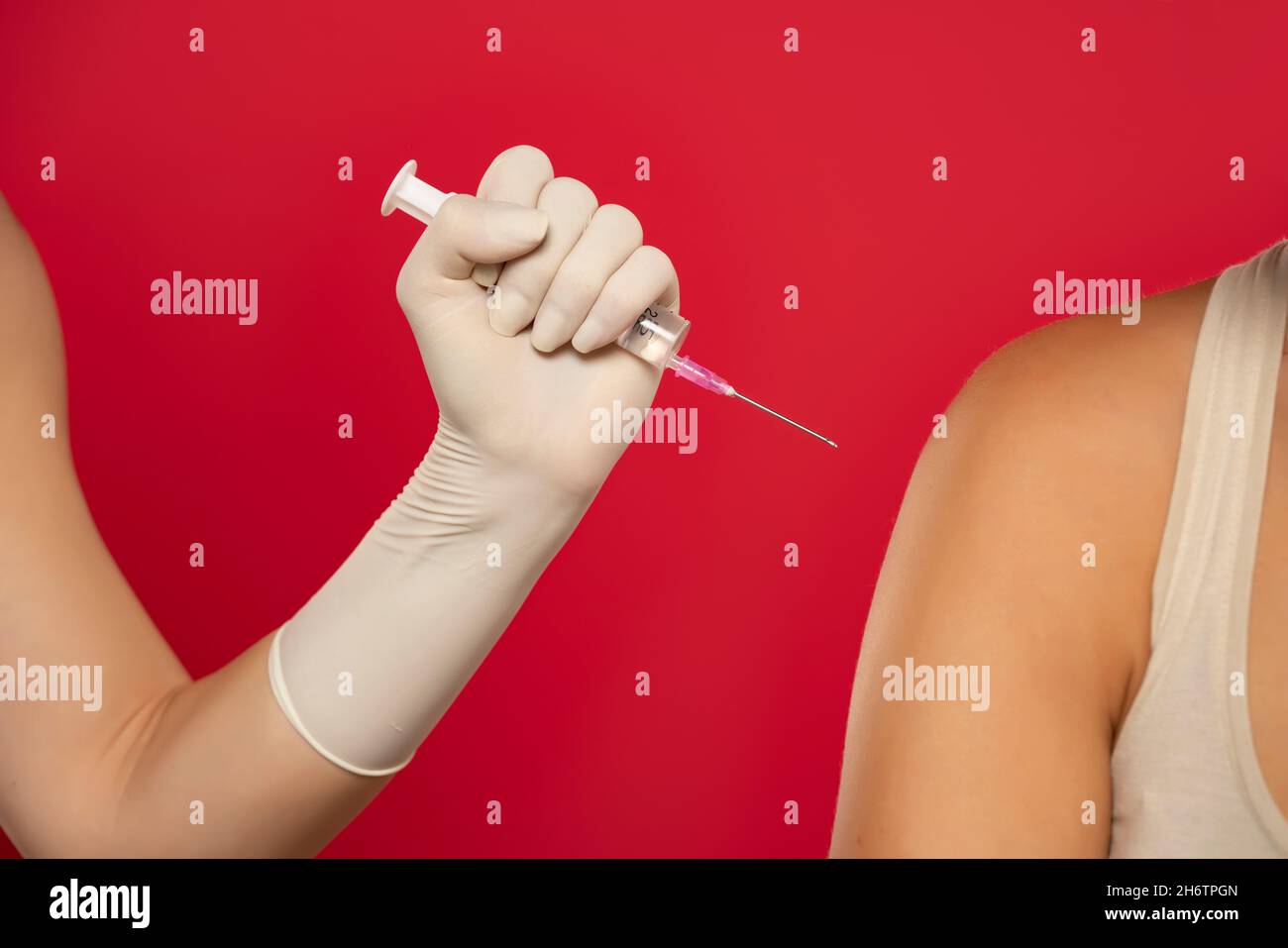 Vaccination d'épaule de manière agressive sur fond rouge Banque D'Images