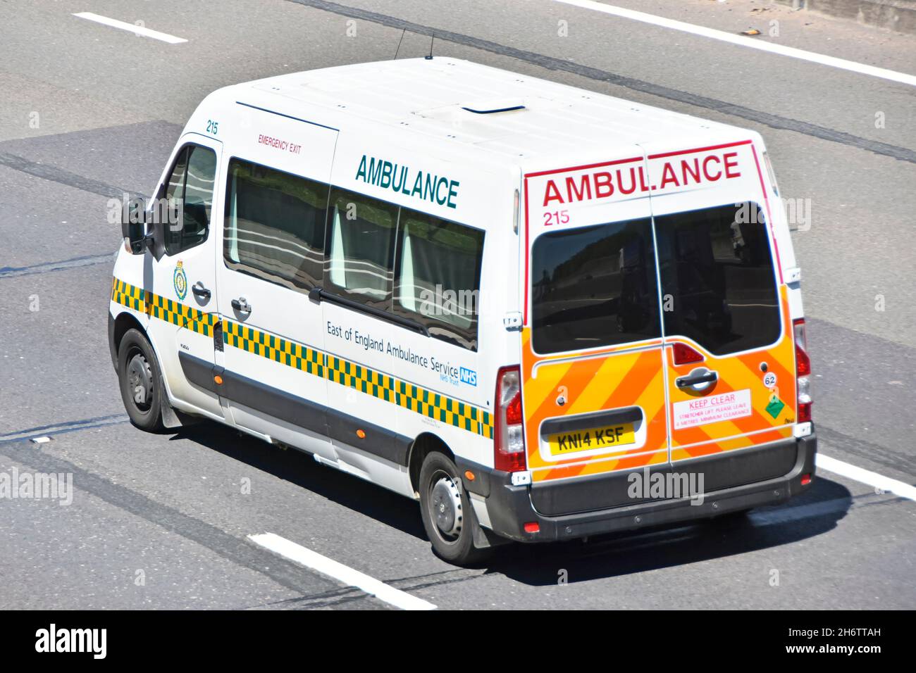 Vue latérale arrière et vue aérienne est de l'Angleterre transfert de patient type ambulance sanitaire NHS avec marquages de véhicule haute visibilité sur l'autoroute britannique Banque D'Images