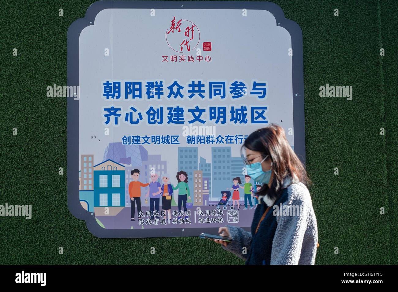 Une jeune fille passe devant un panneau publicitaire présentant des masses de Chaoyang participe à la création d'une ville civilisée à Beijing, en Chine.18 novembre 2021 Banque D'Images