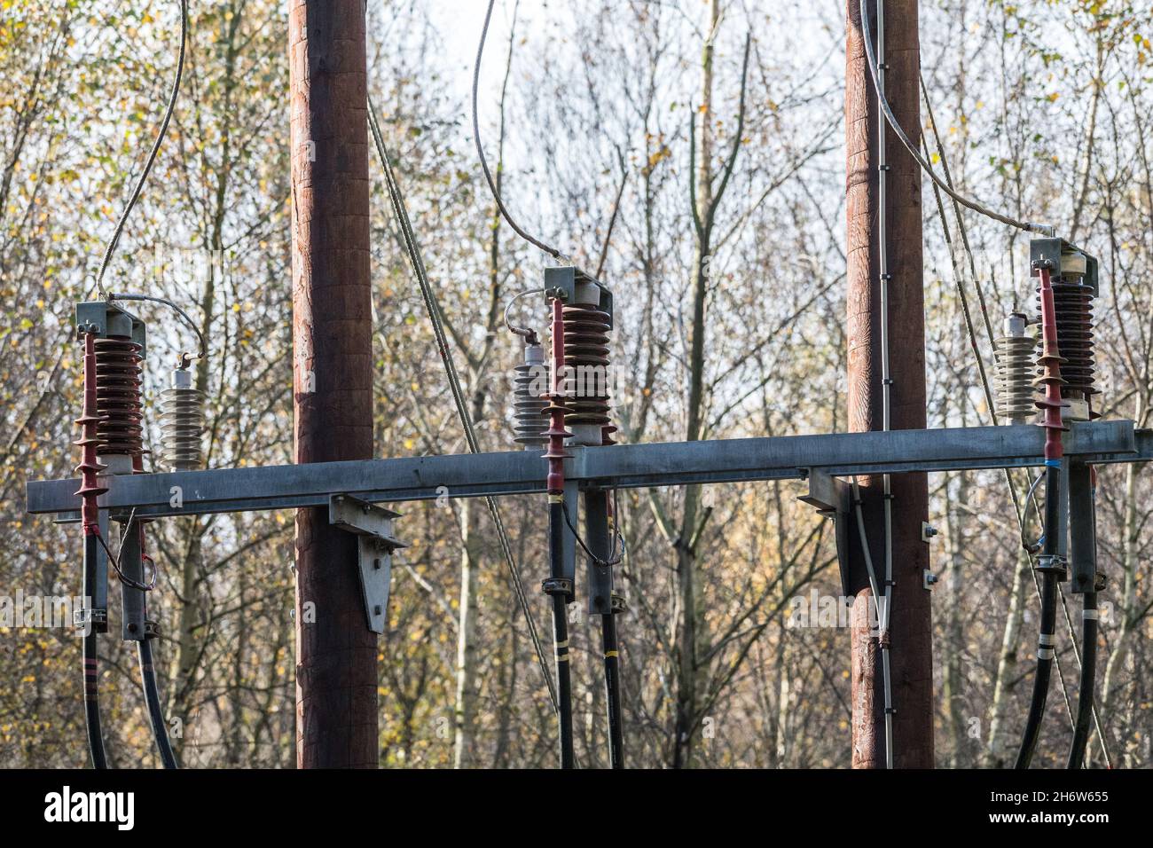 Alimentation électrique en hauteur 33 KV montée sur des poteaux en bois, connexion à un câble d'alimentation souterrain. Banque D'Images