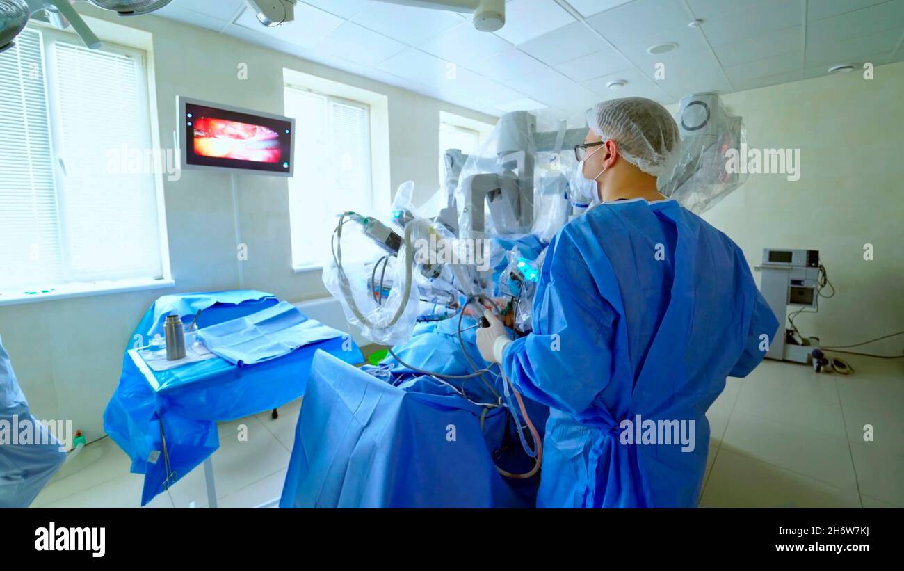 gros plan d'un médecin ou d'un chirurgien effectuant une opération sur un patient avec un robot chirurgical moderne tout en observant un moniteur. Banque D'Images