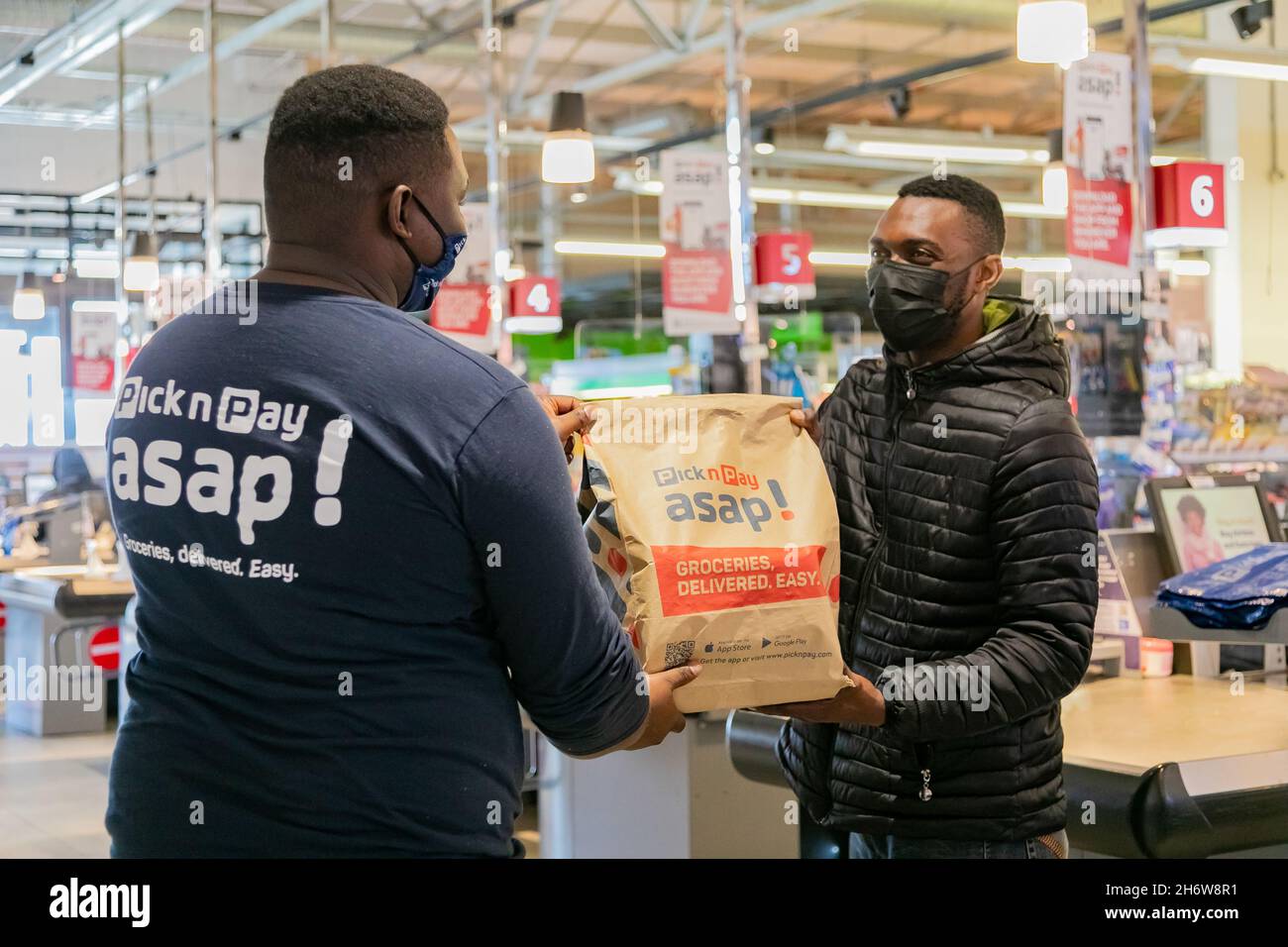 Cape Town, Afrique du Sud - 9 septembre 2021 : le livreur Express Service collecte la commande auprès du personnel au comptoir à l'intérieur de l'épicerie locale Pick n Pay Banque D'Images