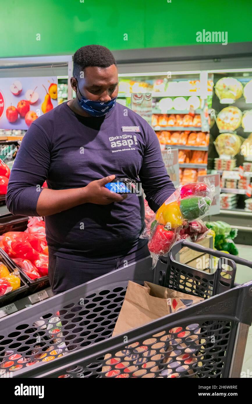 Cape Town, Afrique du Sud - 9 septembre 2021 : un membre du personnel cueille des produits à partir de l'étagère pour un service de livraison express à domicile Banque D'Images
