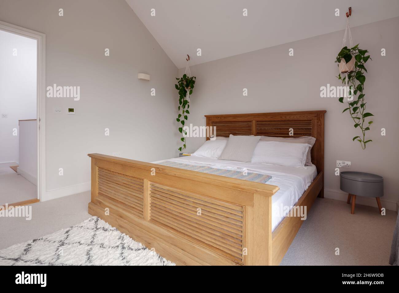 Dry Drayton, Angleterre - 2 août 2019 : chambre.Grand lit en bois et petite table décorée simplement dans des tons de blanc Banque D'Images