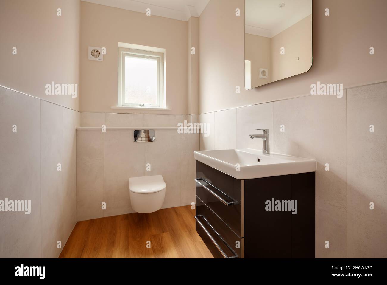 Clafring, Angleterre - avril 6 2020: Nouvelle maison vestiaire ou salle de bain avec WC mural wc et lavabo avec murs carrelés et plancher en bois Banque D'Images